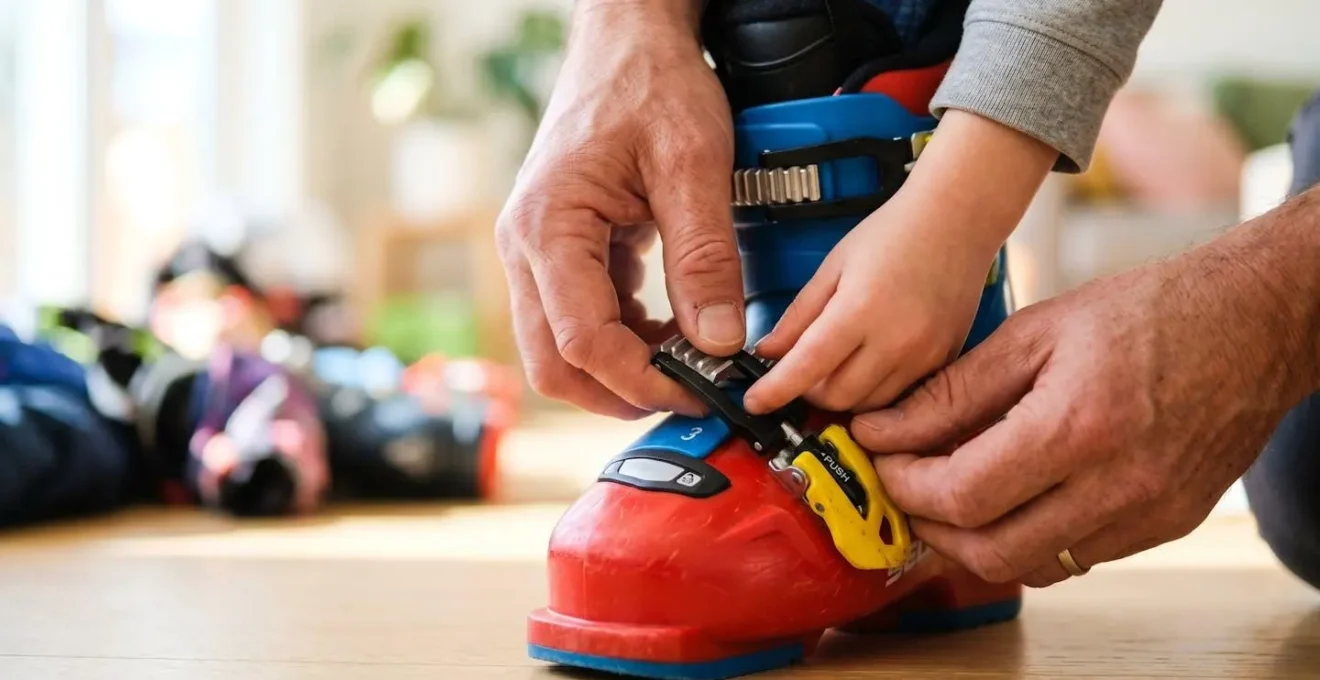 Gros plan sur les mains d'un adulte aidant un enfant à ajuster les boucles de sa chaussure de ski colorée